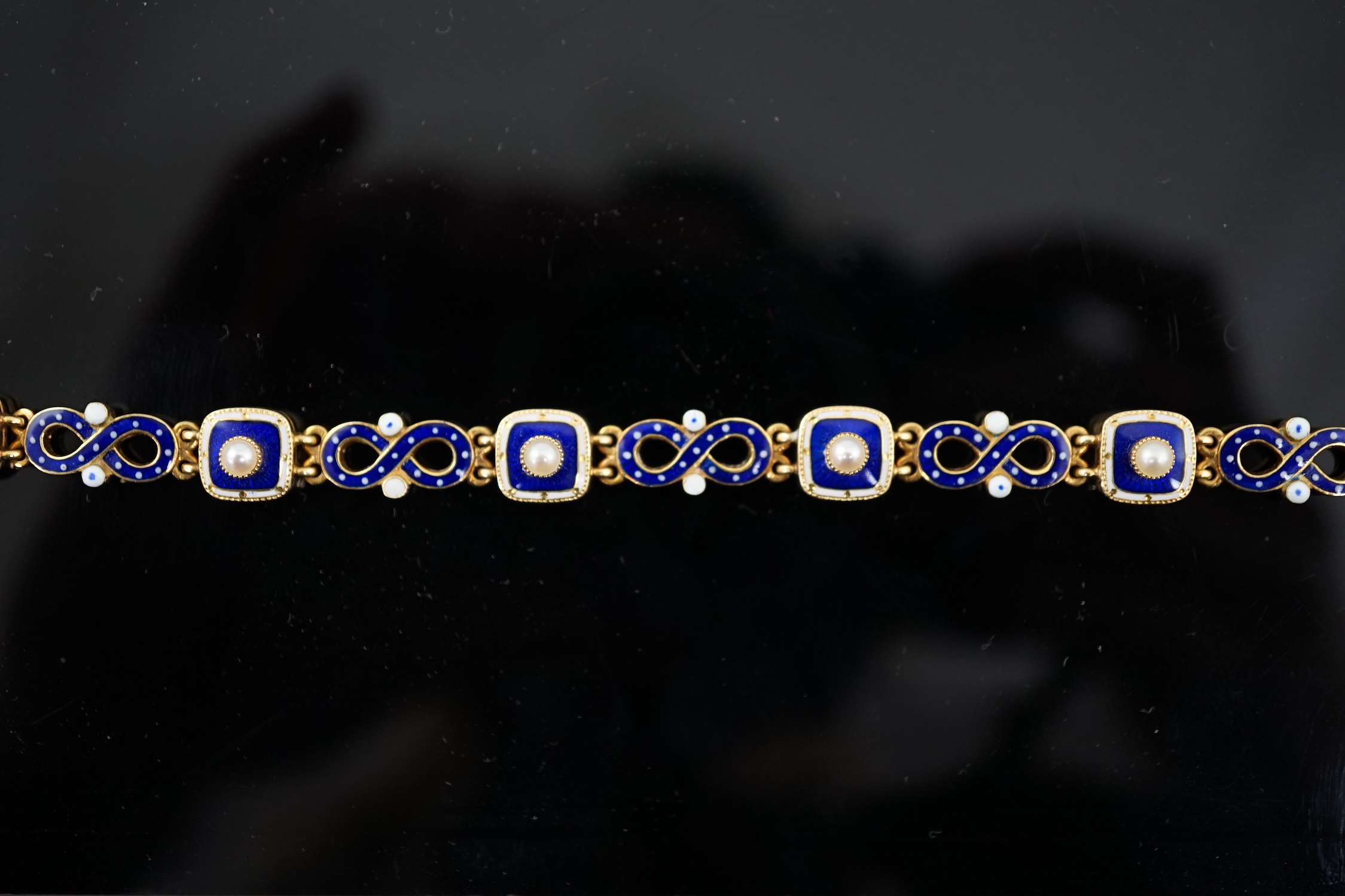 An early 20th century gold (tests as 18ct), two colour enamel and spilt pearl set bracelet